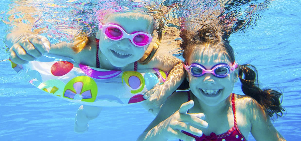 Two funny girls playing in swimming pool. Vacation and travel concept